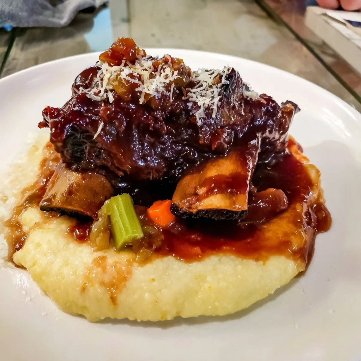 Tender braised beef short ribs glistening in rich sauce, served over a bed of creamy polenta.