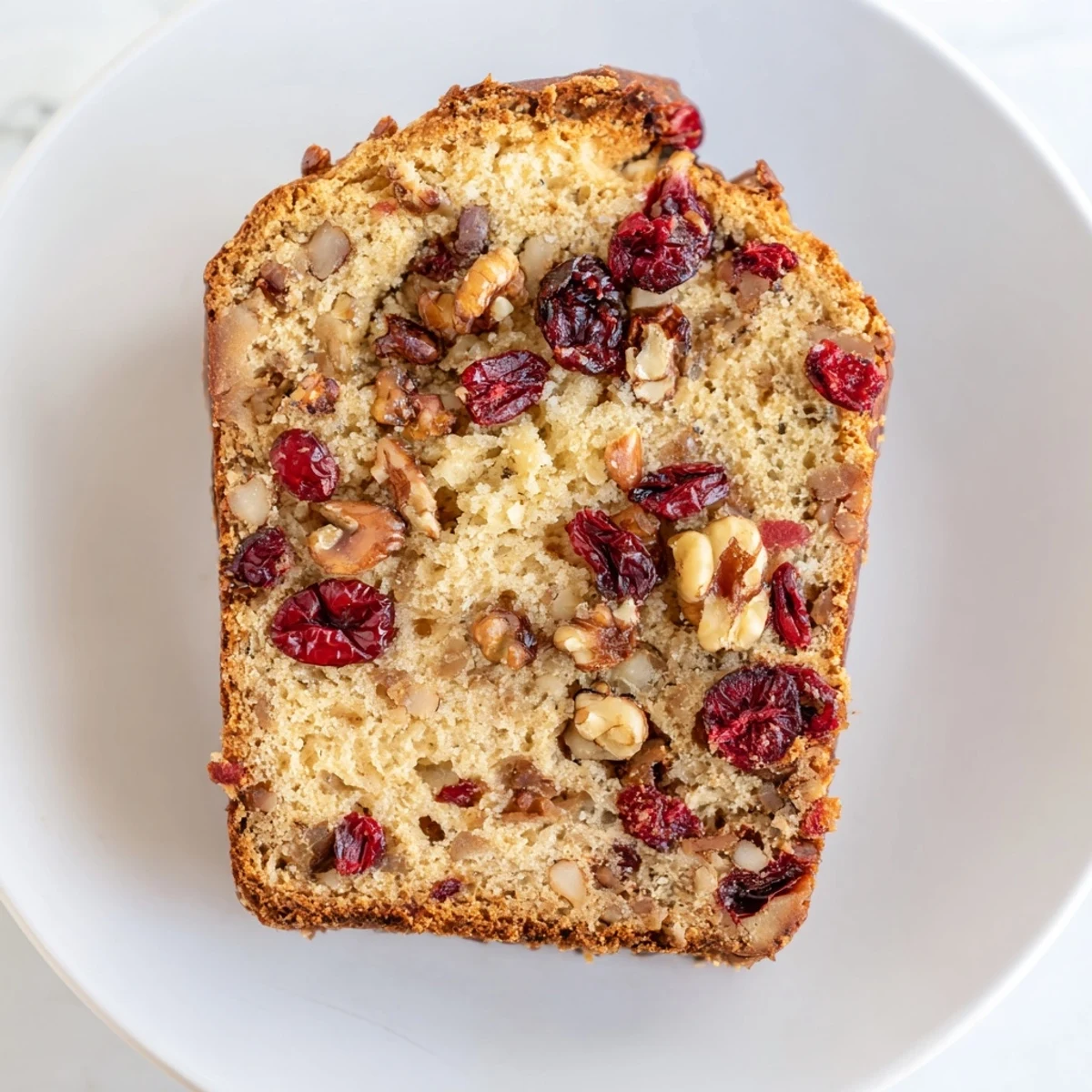 Golden, freshly baked Cranberry Walnut Bread Loaf, with visible tart cranberries and walnuts, ready to eat.
