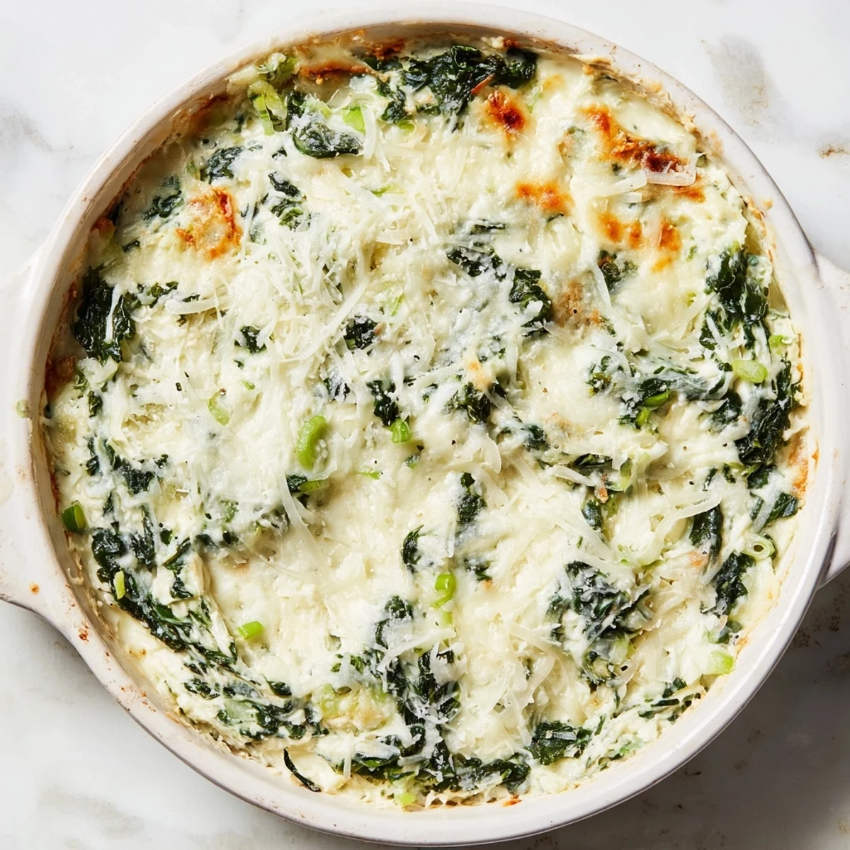 Warm, cheesy Spinach Dip, bubbling in a baking dish, ready to be scooped up.