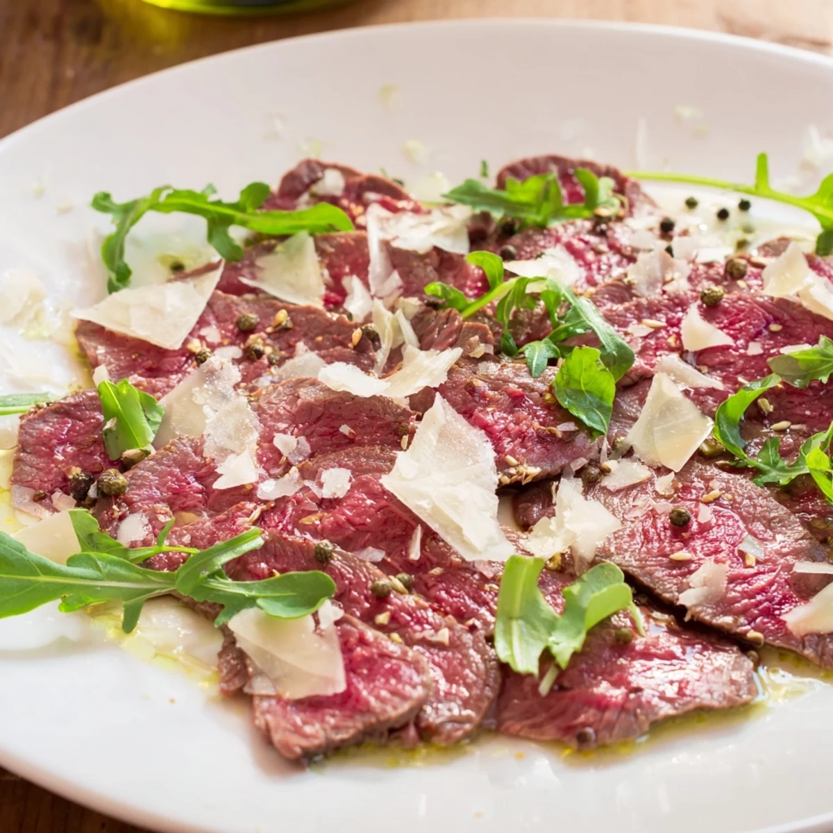 Delicious beef carpaccio, artfully arranged on a plate with fresh arugula and salty capers.