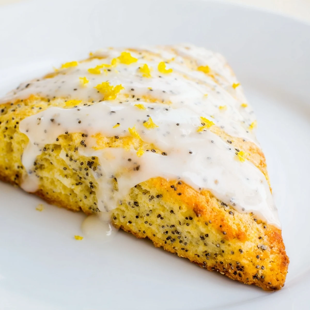 Warm Lemon Poppy Seed Scones with glazed tops, served beside a steaming cup of black tea.