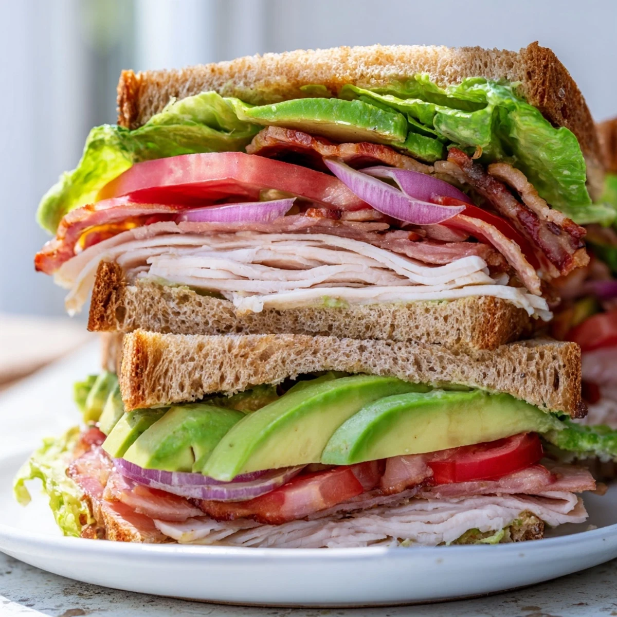 Triple-decker Turkey Club Sandwich stacked with crispy turkey bacon, creamy avocado, and fresh lettuce and tomato.