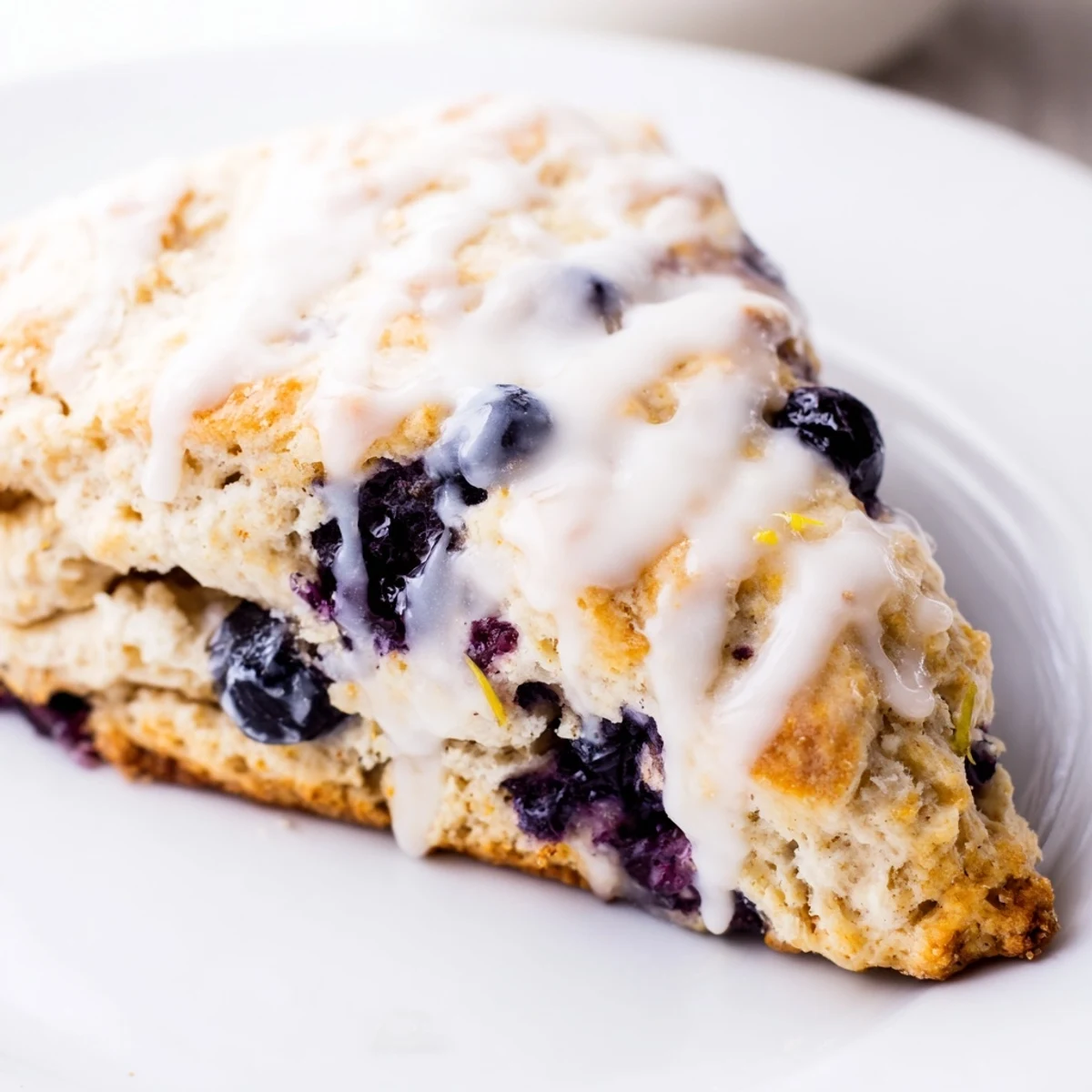 Warm Lemon Blueberry Scones with Vanilla Glaze paired with a cup of coffee for breakfast.