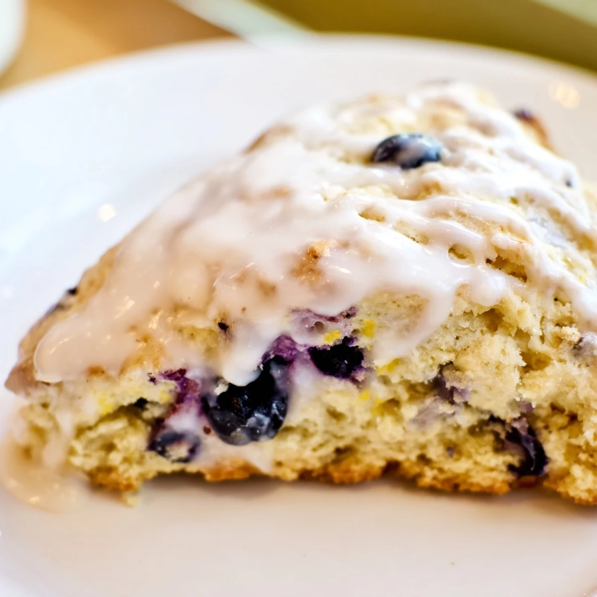 Golden Lemon Blueberry Scones with Vanilla Glaze showing juicy blueberries and bright lemon zest.