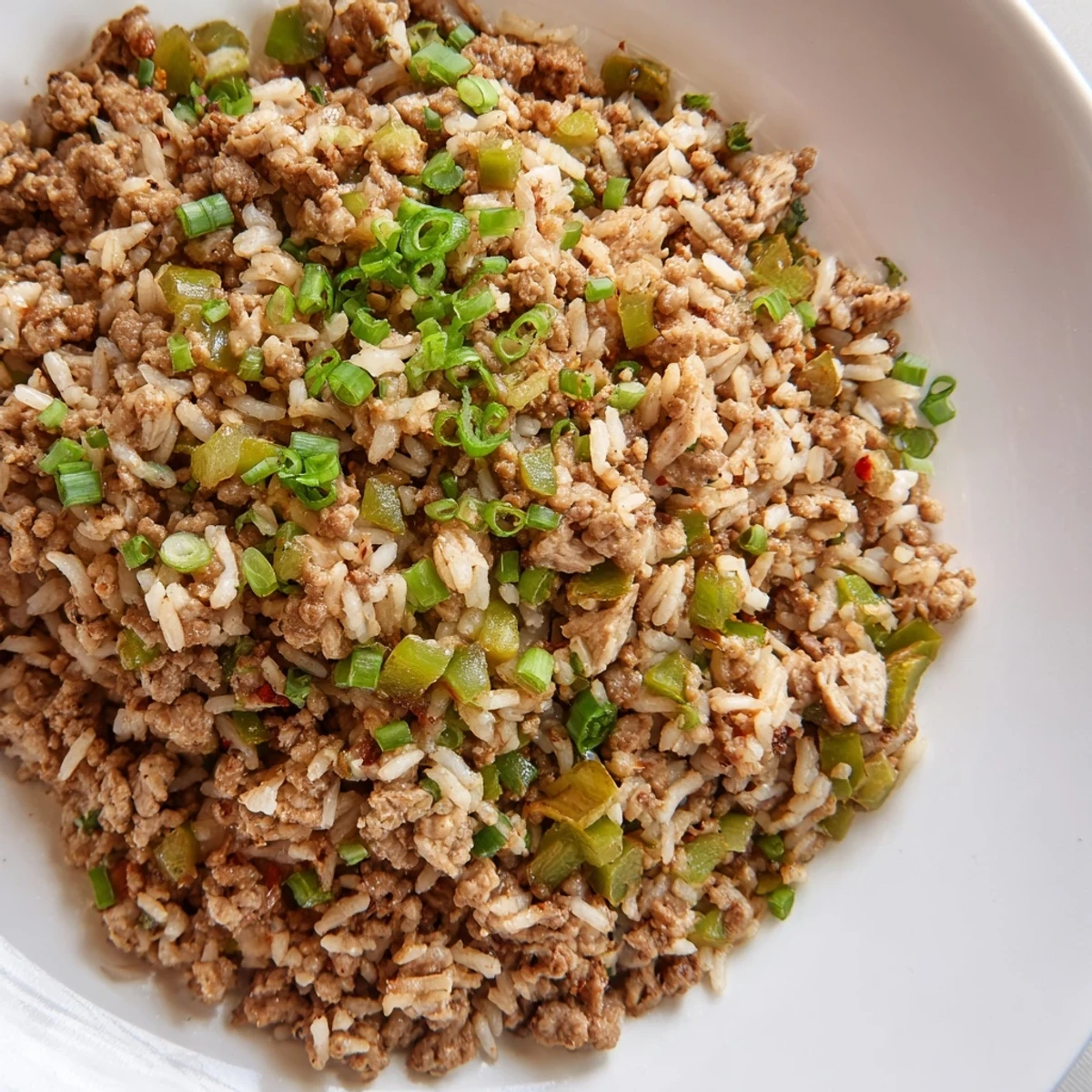 Cajun Dirty Rice with Ground Turkey features golden-brown turkey and colorful peppers simmered in a savory, spicy broth, served steaming hot in a rustic skillet.