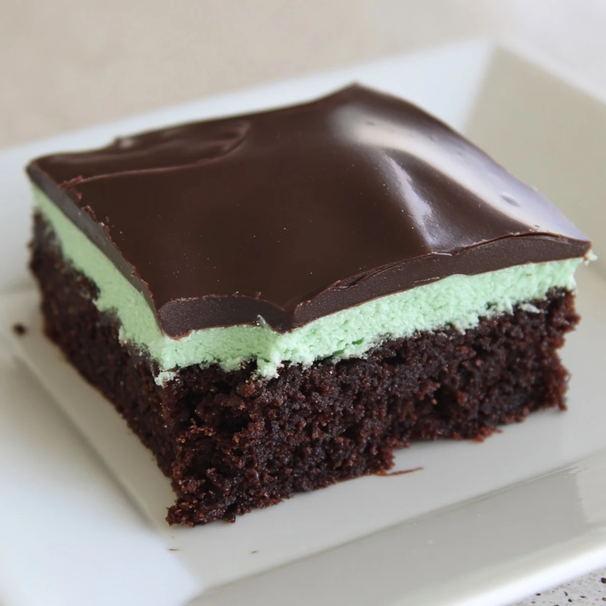 A close-up of Shamrock Mint Brownies with Chocolate Ganache, showcasing the fudgy texture and glossy green mint layer.