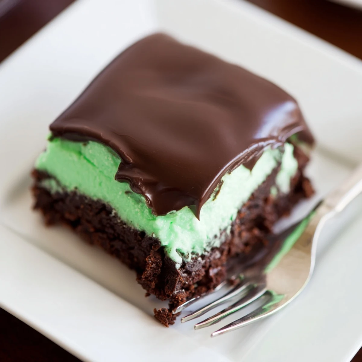 A close-up of Shamrock Mint Brownies with Chocolate Ganache, featuring a rich green mint frosting and a shiny dark chocolate topping.
