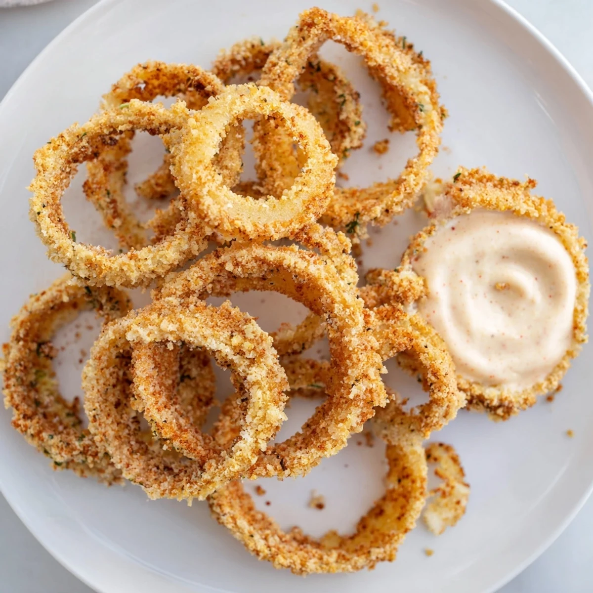 Homemade crispy onion rings with smoky paprika and tangy chipotle mayo, ready to enjoy with lemon wedges on the side.