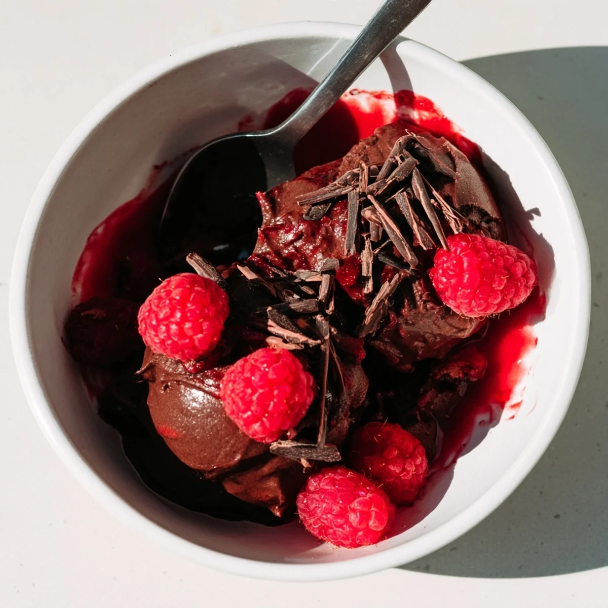 A close-up of creamy chocolate mousse garnished with chocolate curls and fresh mint leaves.