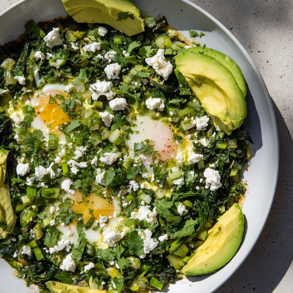 Vibrant Green Shakshuka with Spinach and Feta breakfast dish featuring poached eggs and crumbled feta cheese.