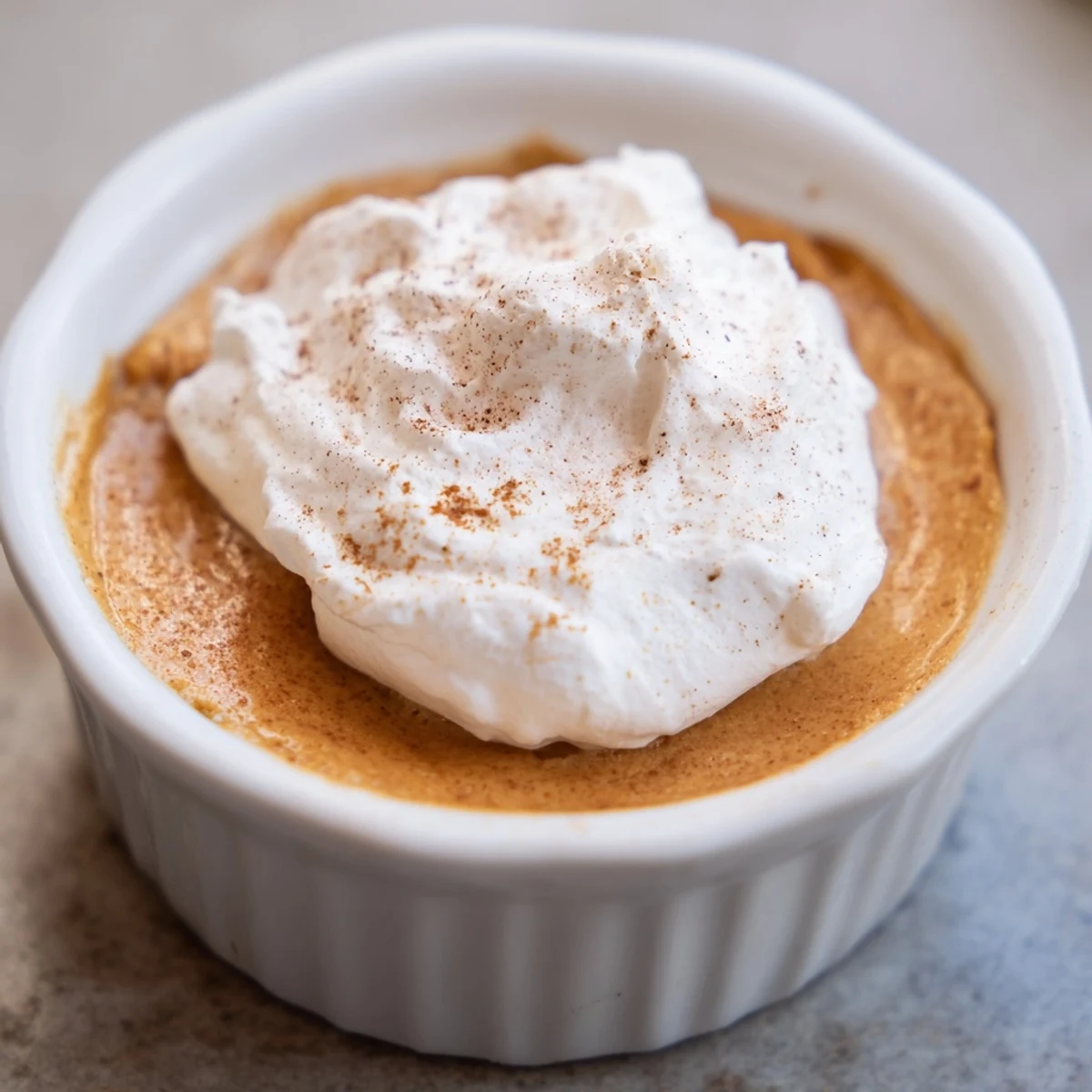 Warm Baked Pumpkin Spice Pudding scooped from a baking dish, showing creamy texture and aromatic fall spices.