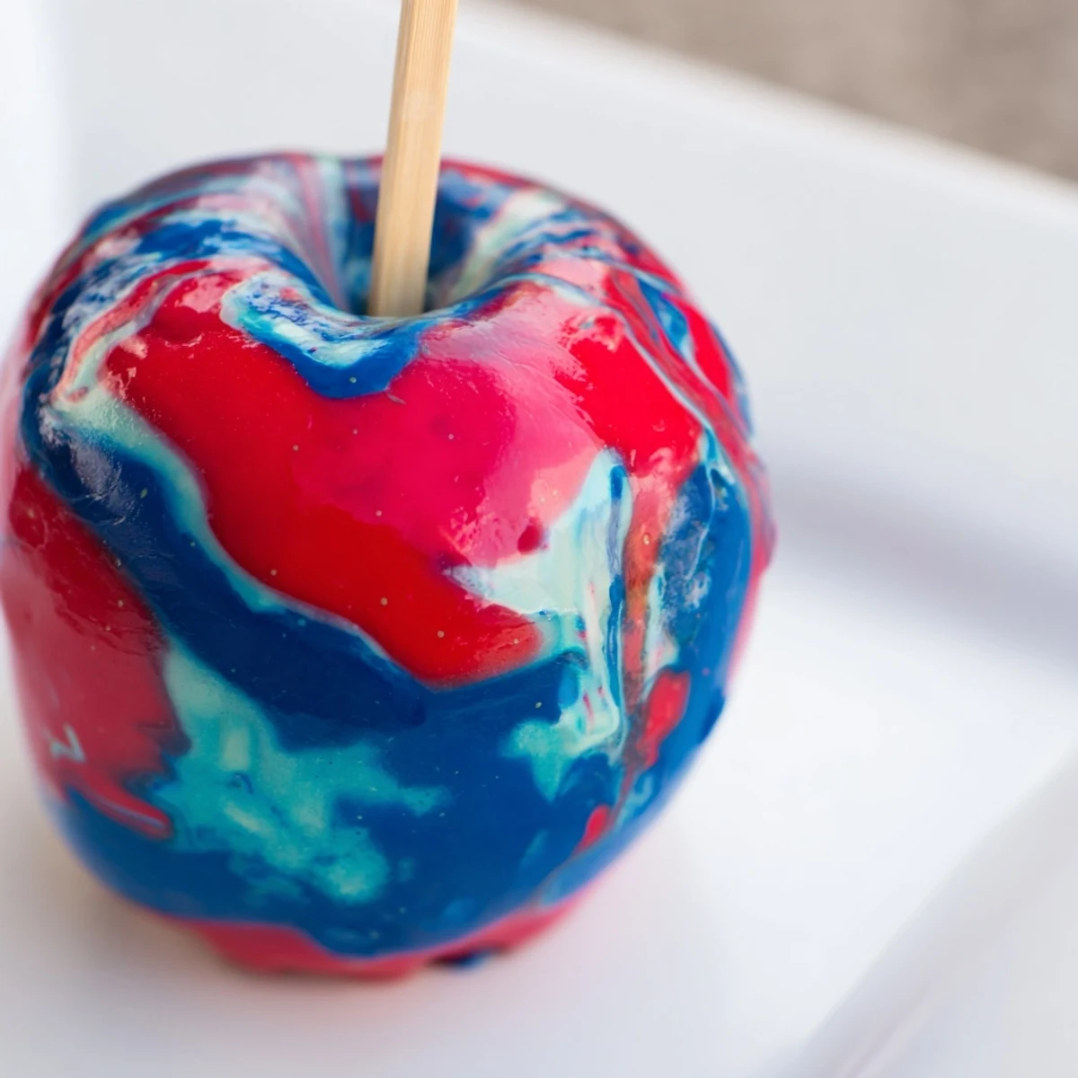 Glossy Marbled Effect Candy Apples with vibrant red and blue swirls displayed at a holiday dessert table.