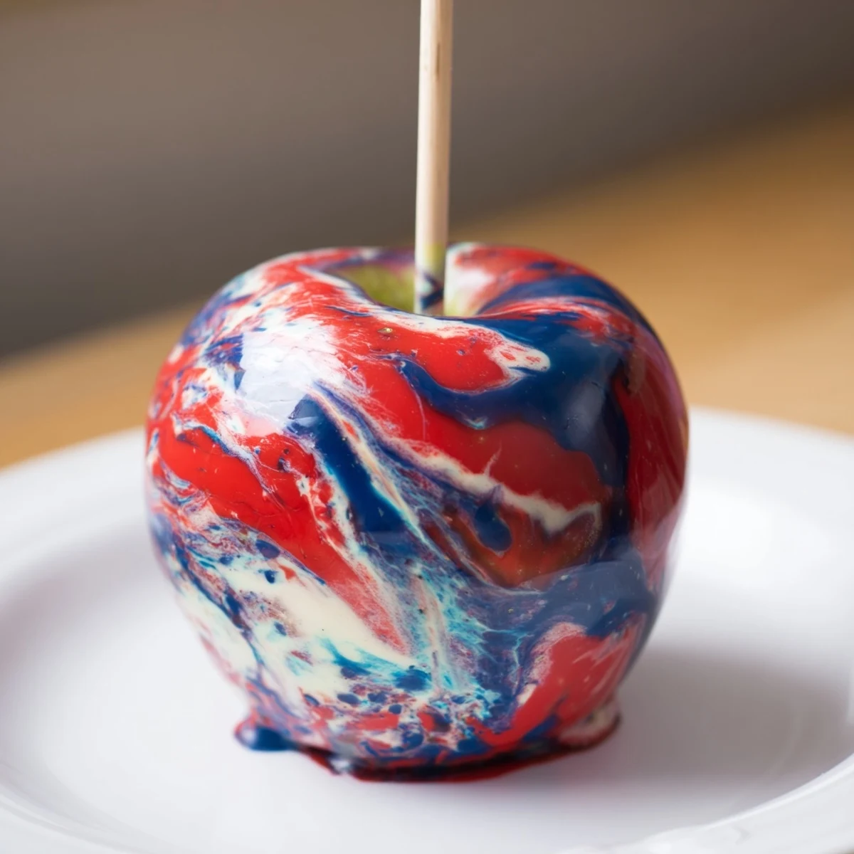 Freshly dipped Marbled Effect Candy Apples on parchment, their crisp apple interior visible beneath the colorful shell.