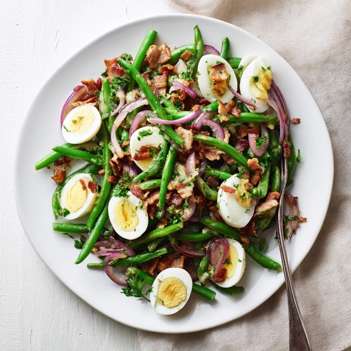 A close-up of the Green Bean, Bacon, and Egg Salad with crisp beans and creamy egg quarters.