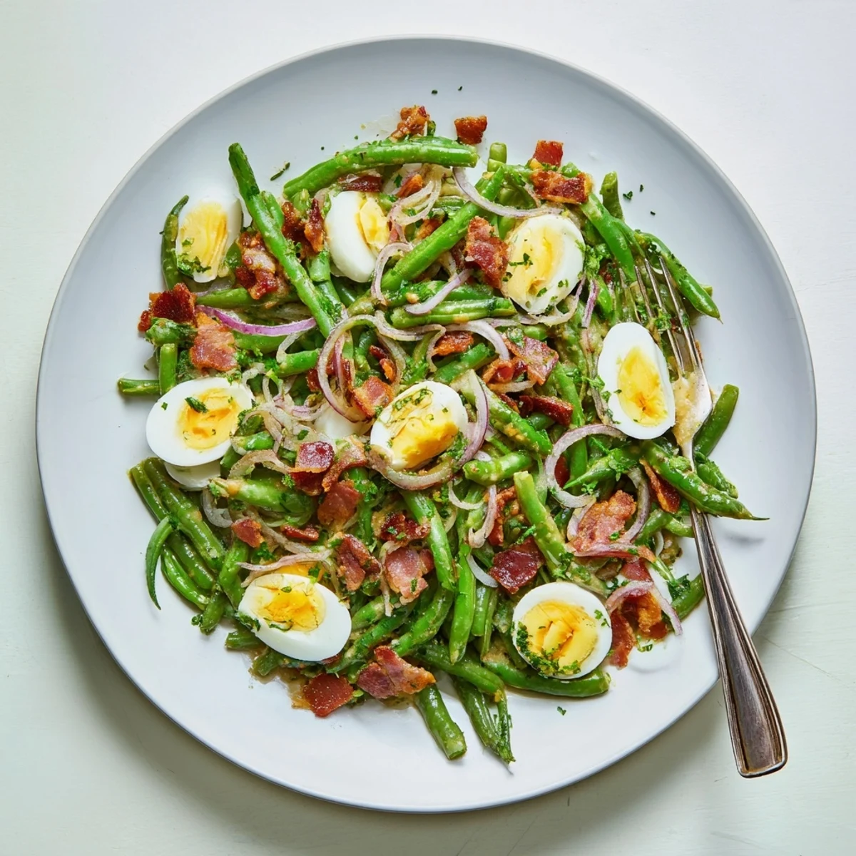 Freshly plated Green Bean, Bacon, and Egg Salad, garnished with parsley and a tangy Dijon vinaigrette.