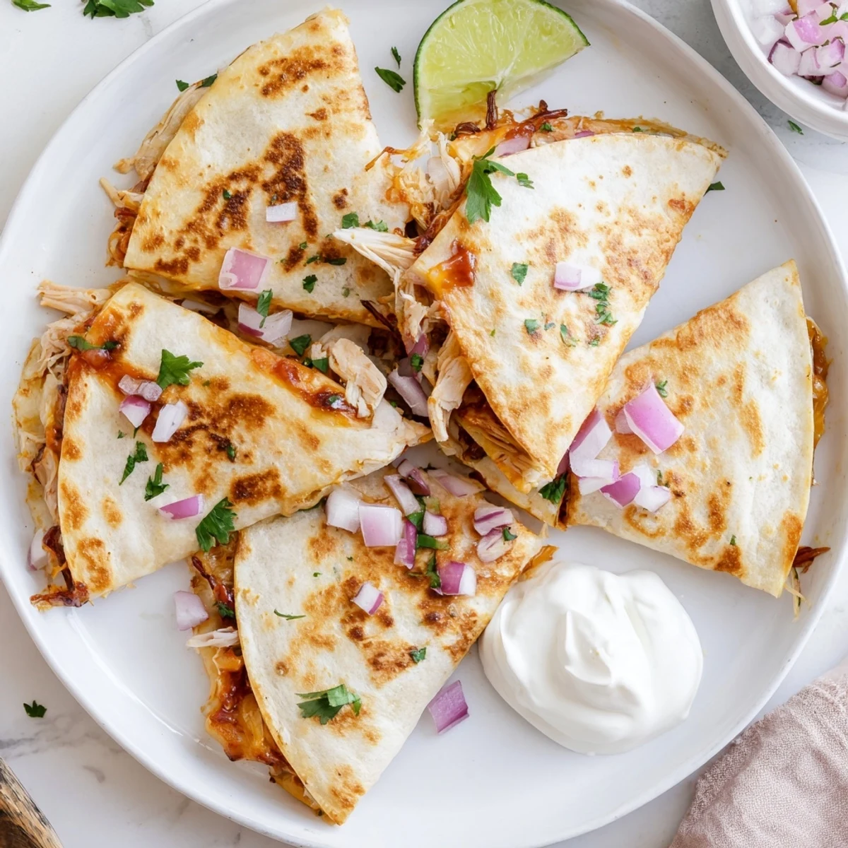 Close-up view of a sliced Hot Honey BBQ Chicken Quesadilla revealing tender BBQ chicken, diced red onion, and gooey melted cheese.