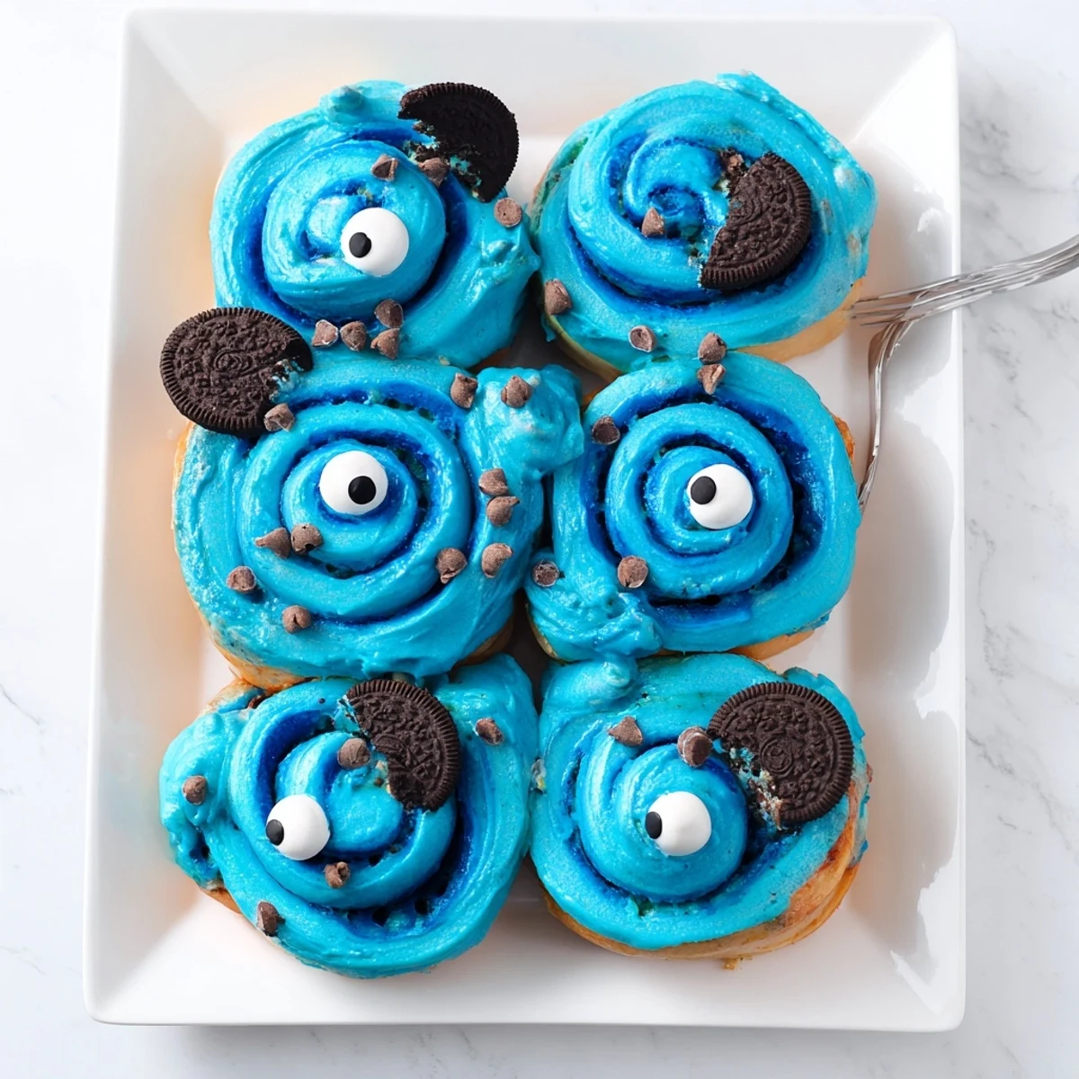 Glazed blue Cookie Monster cinnamon rolls paired with milk, perfect for a fun family dessert spread.
