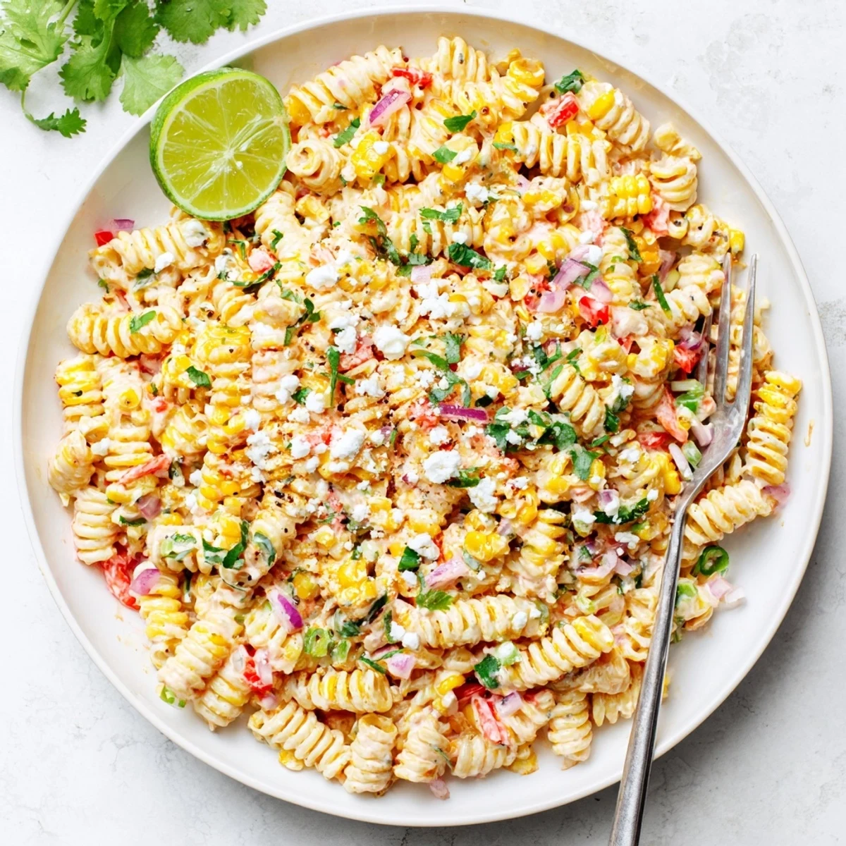 Juicy Street Corn Pasta Salad with cotija, lime wedges, and chili powder for a refreshing side.