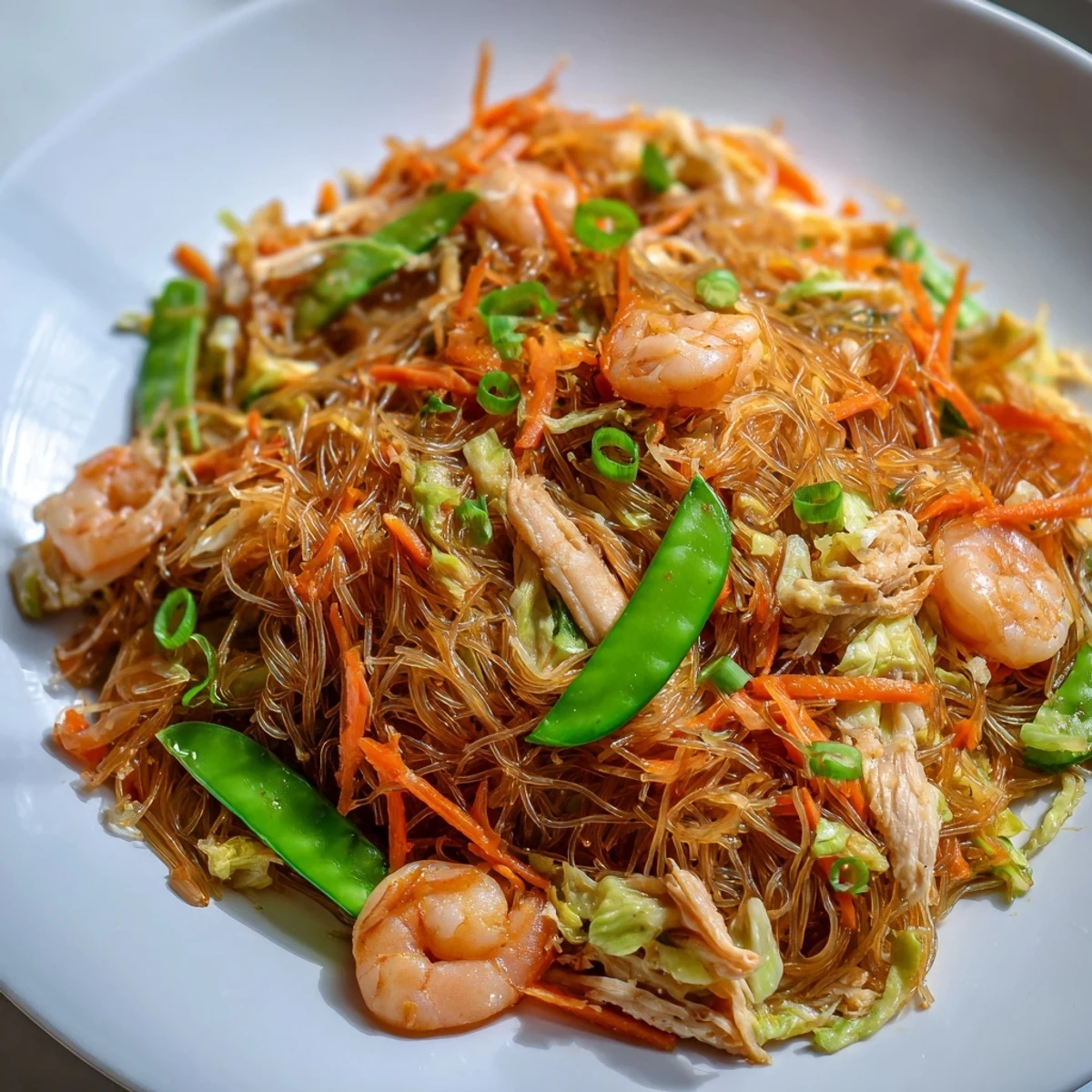 Tender Pancit Bihon rice vermicelli tossed with juicy shrimp chicken strips and vibrant julienned carrots cabbage