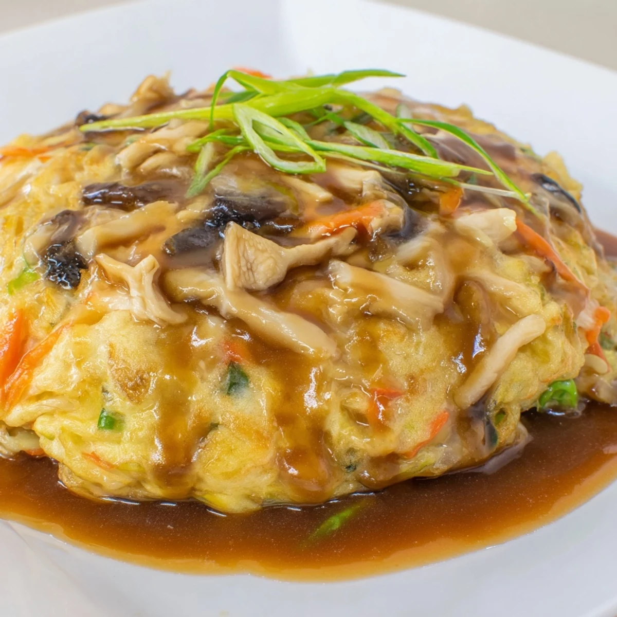 Chinese-American Egg Foo Young omelet with bean sprouts, carrots, and savory sauce drizzled generously