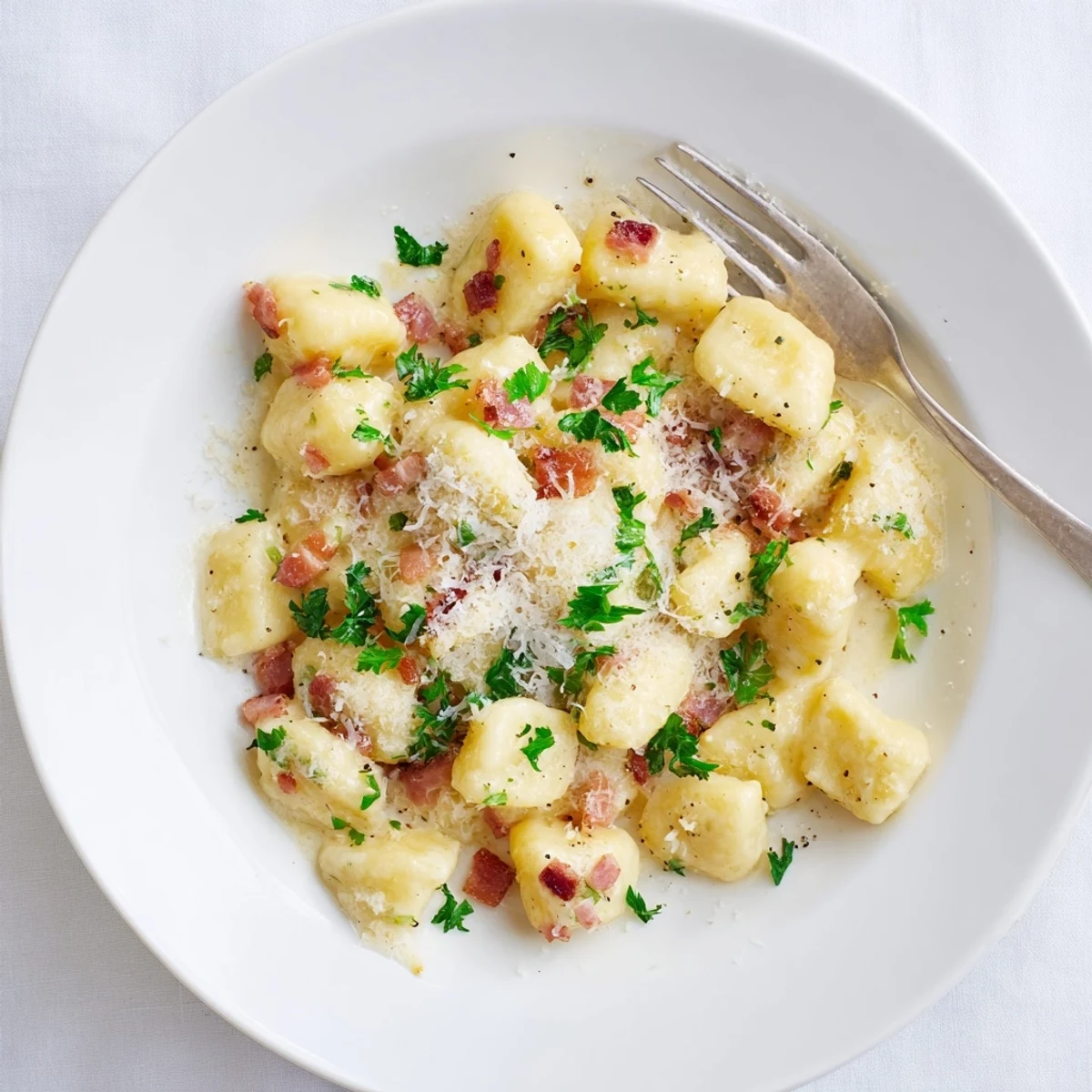 Golden Gnocchi Carbonara with bacon and Parmesan cheese sprinkled on top ready to serve