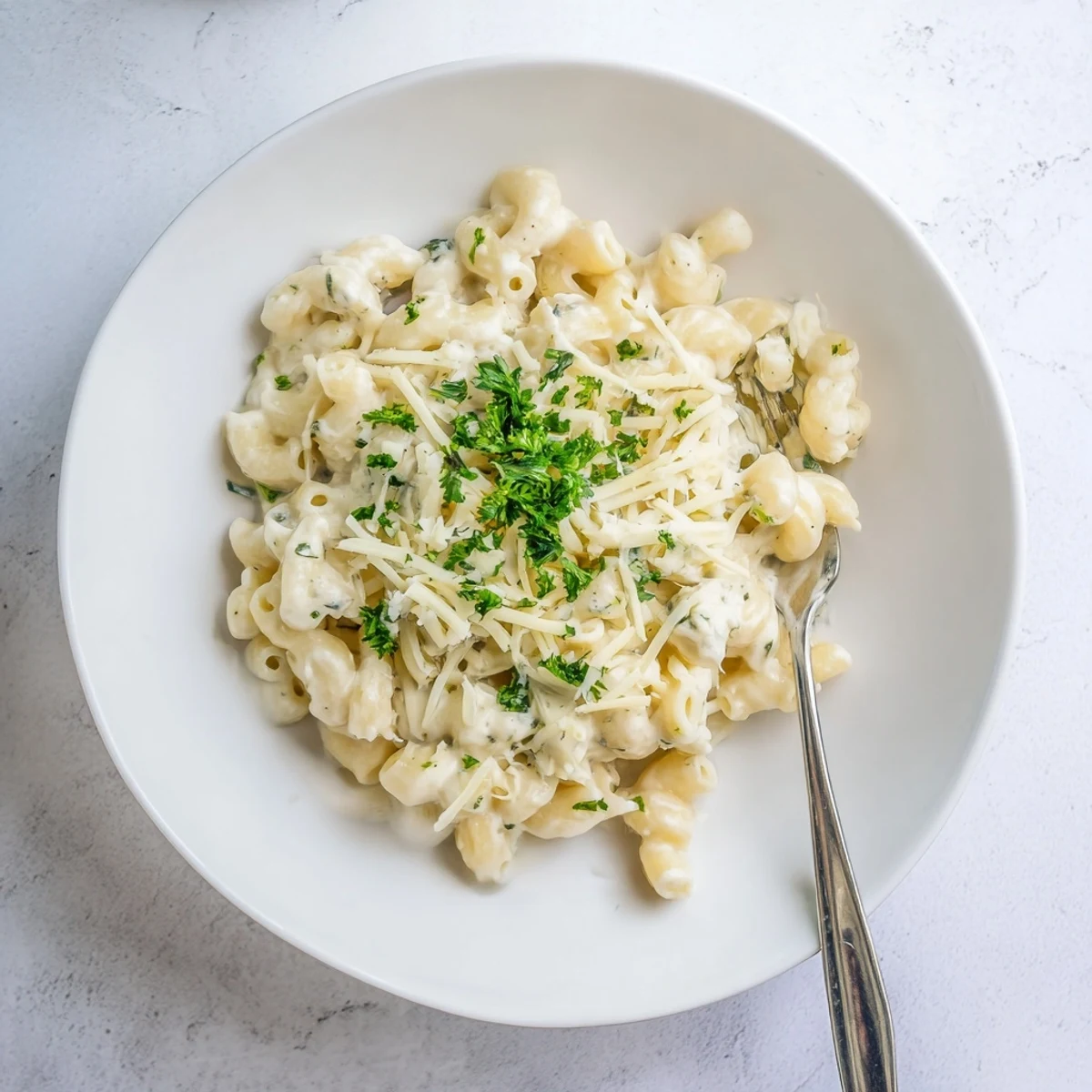 Bowl of rich homemade Boursin mac and cheese topped with fresh parsley and extra grated cheese