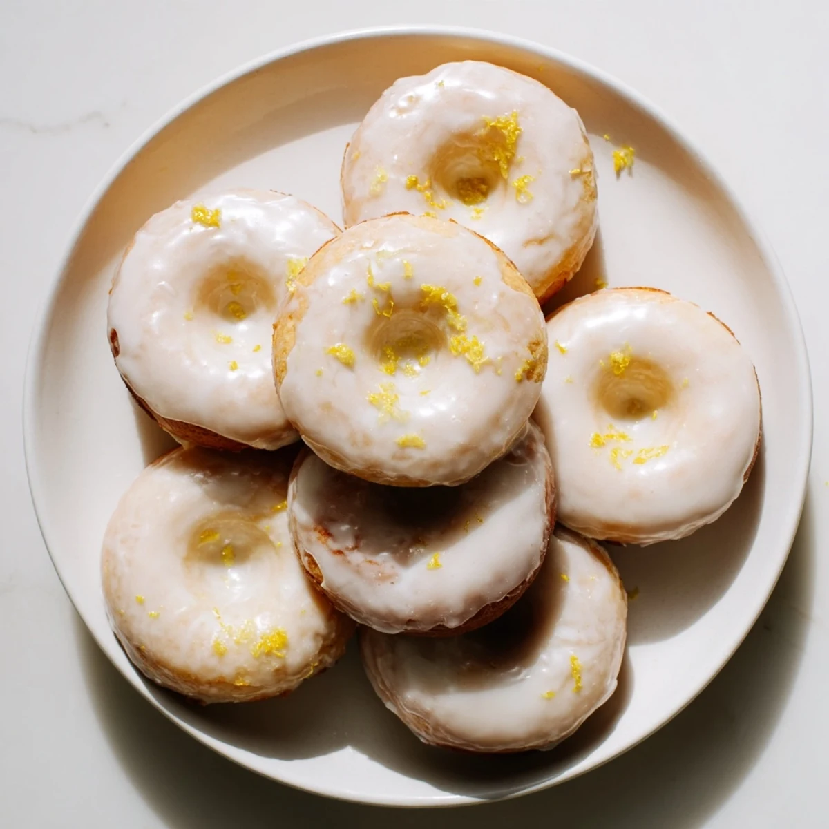 Soft chewy lemon mochi donuts topped with zesty glaze on a white wire rack