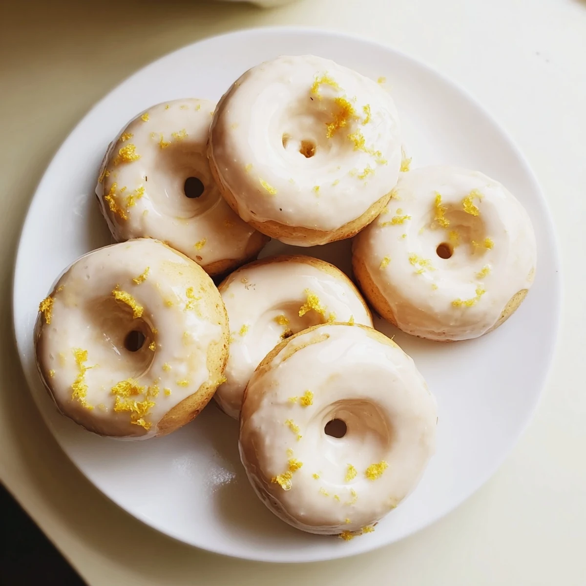 Golden gluten-free lemon mochi donuts drizzled with bright lemon glaze and fresh zest
