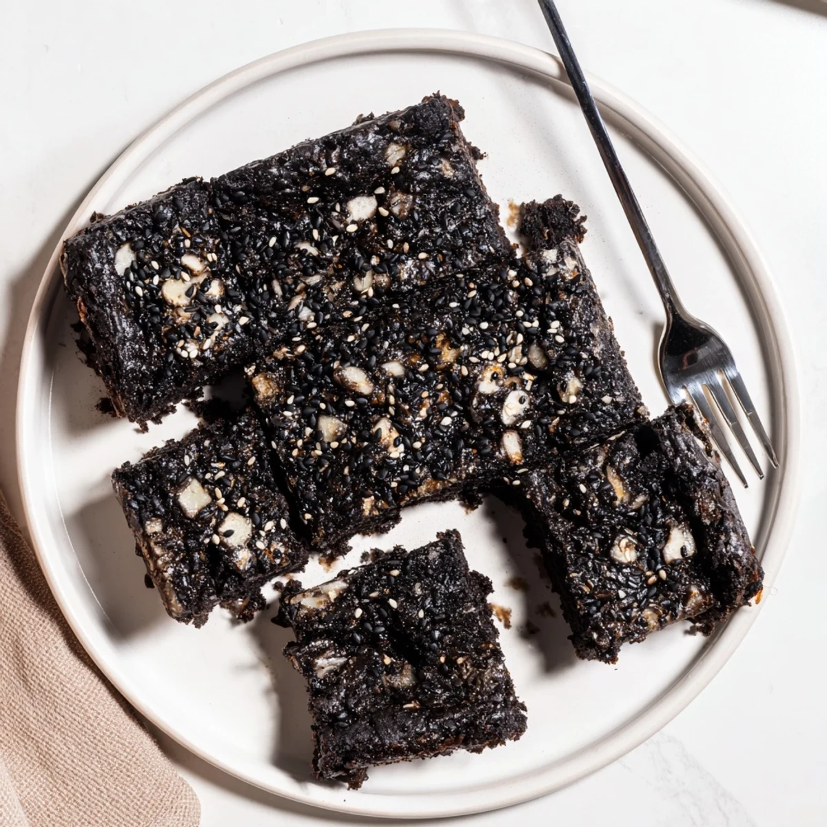 Chewy black sesame blondies sprinkled with toasted seeds on a golden square