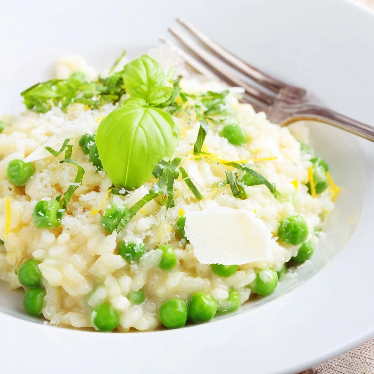 Close-up of Italian spring pea risotto finished with lemon zest, basil ribbons and nutty Parmesan