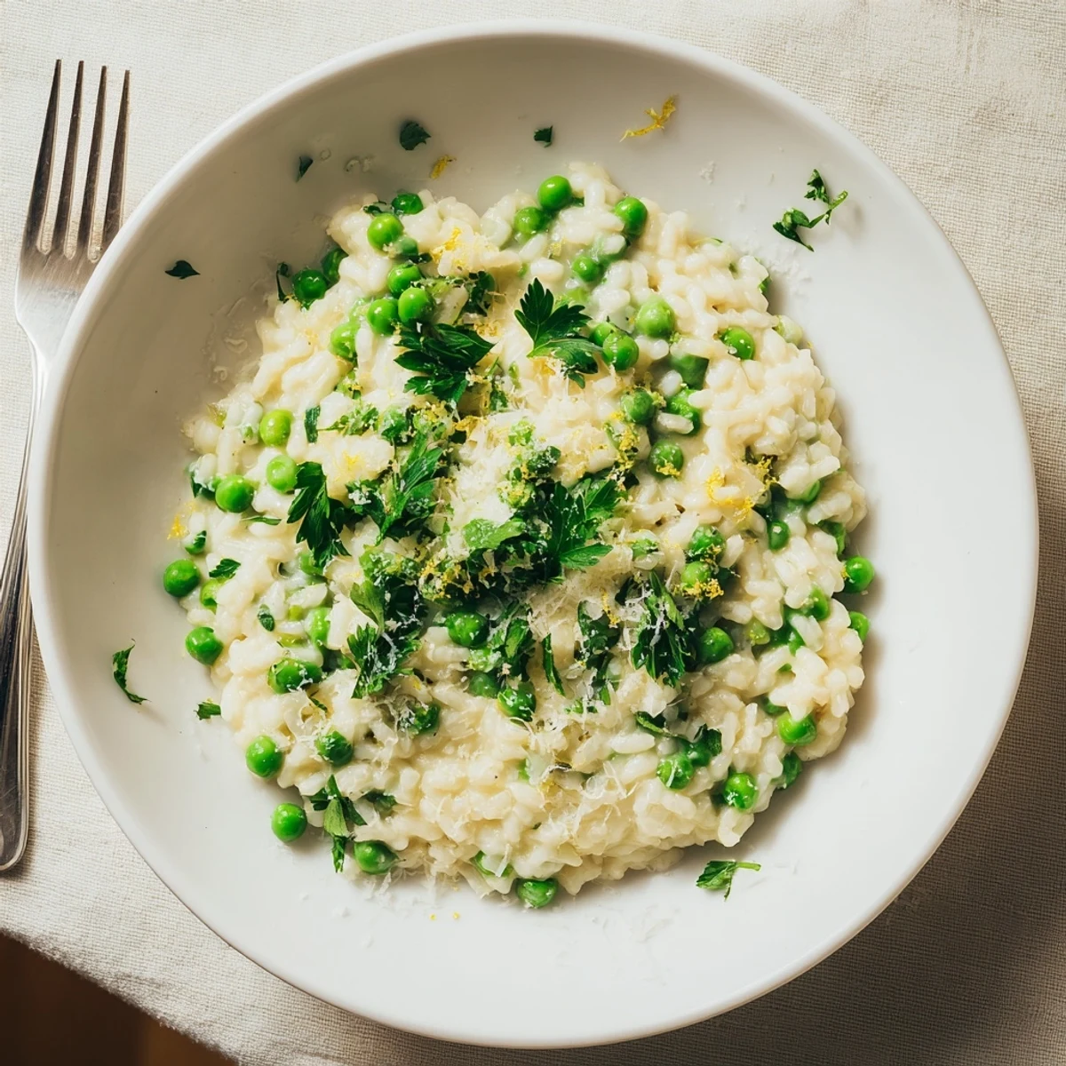 Creamy spring pea risotto topped with fresh grated Parmesan and bright green herbs in a white bowl