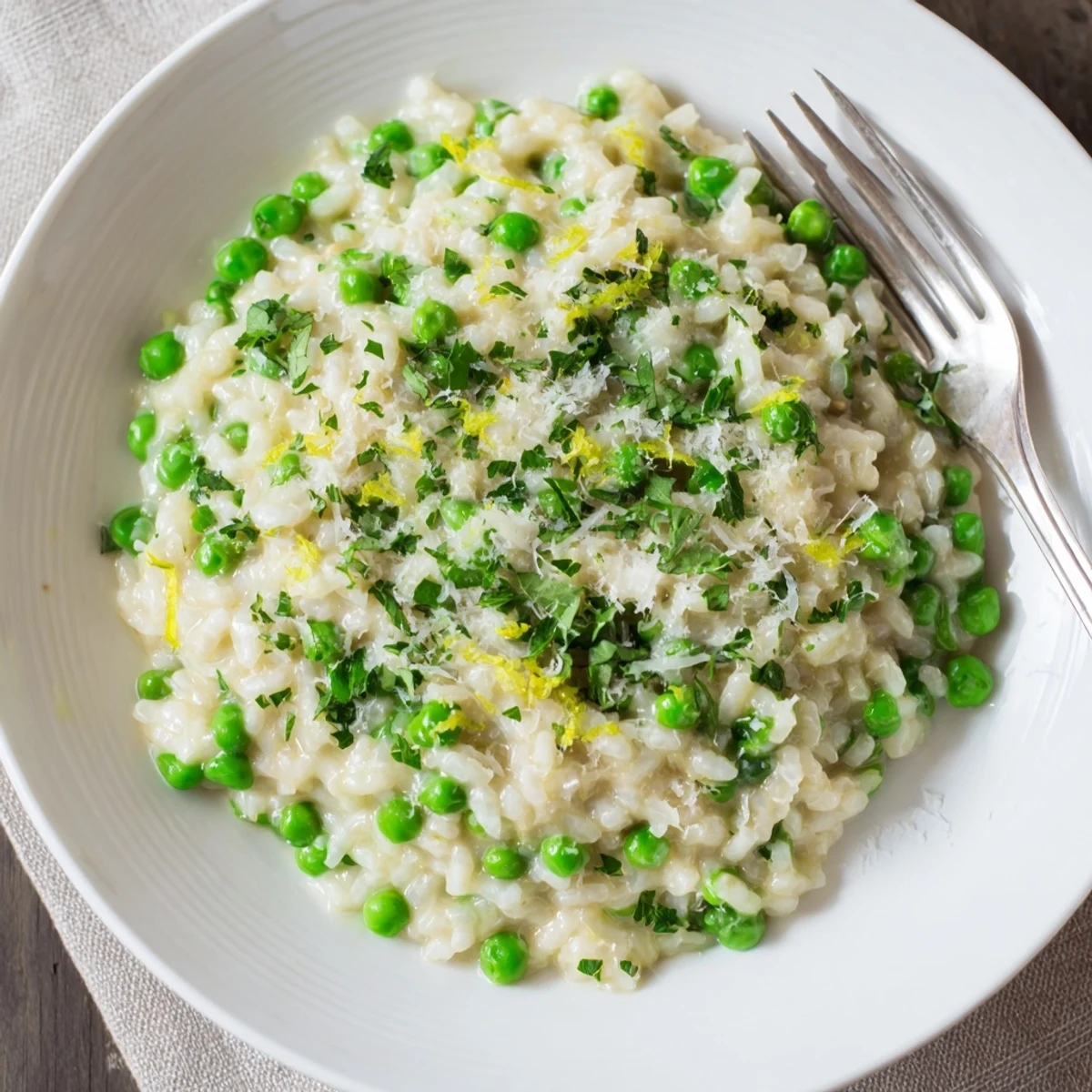 Vibrant spring pea risotto steaming in a rustic bowl with lemon zest and chopped parsley garnish