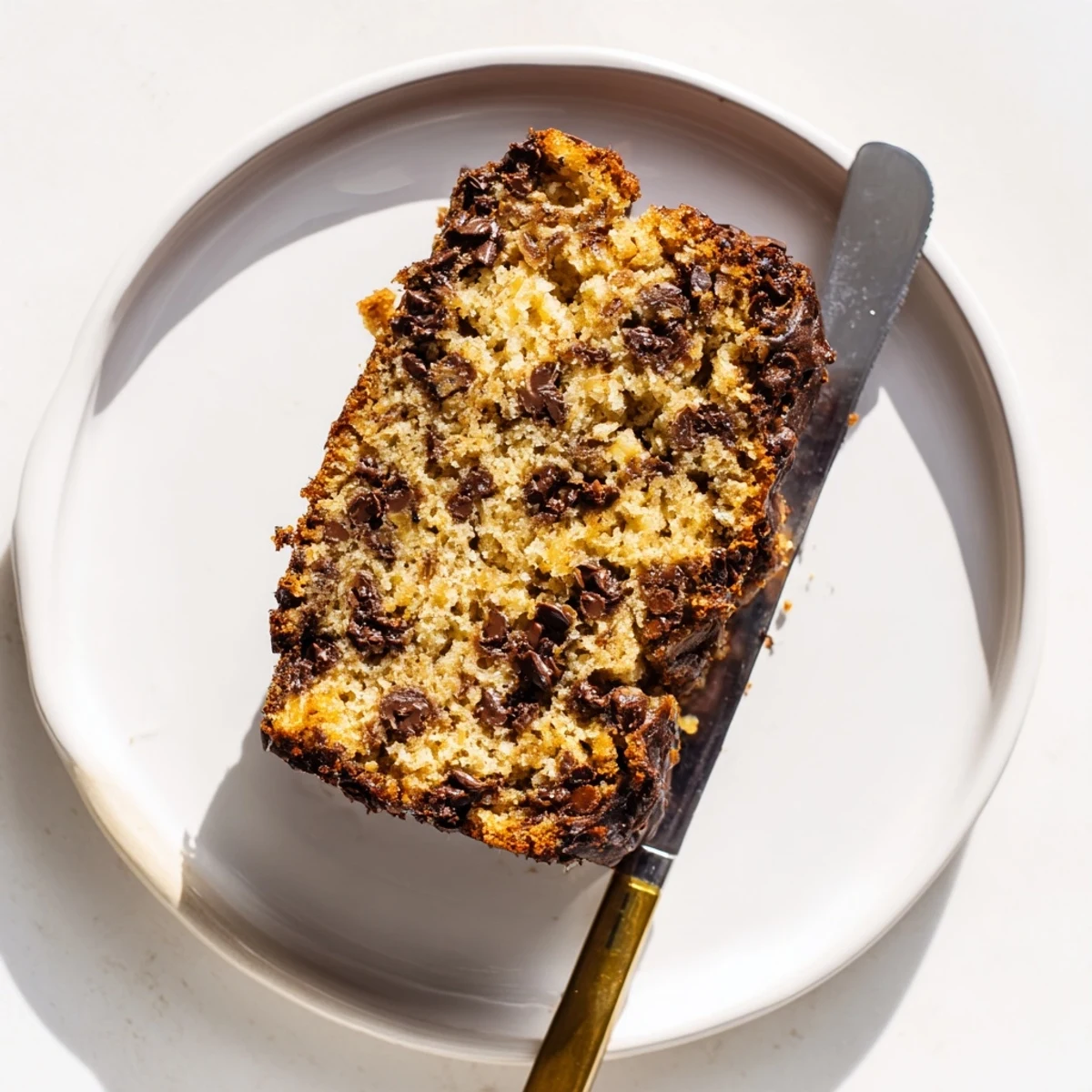Thick slice of moist classic chocolate chip banana bread showing tender crumb and scattered semi-sweet chocolate chips