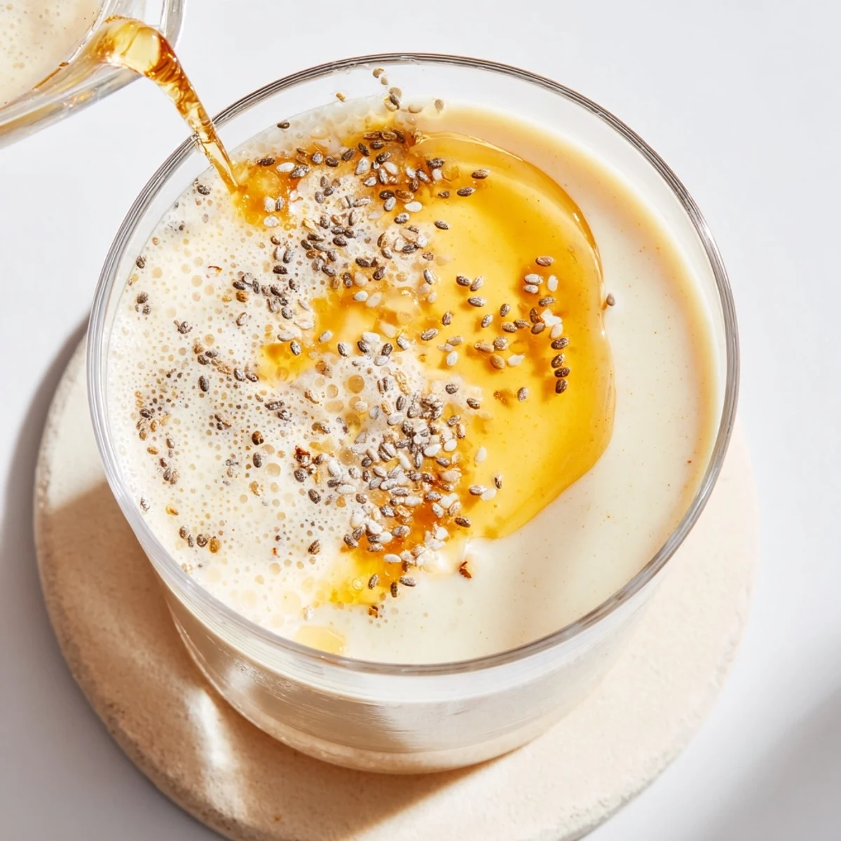 Thick creamy Greek yogurt banana smoothie poured into a glass with fresh banana slices