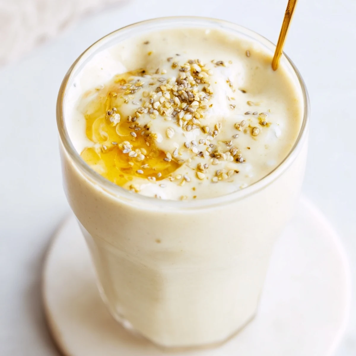 Frosty blended Greek yogurt banana smoothie topped with cinnamon and chia seeds in a tall glass