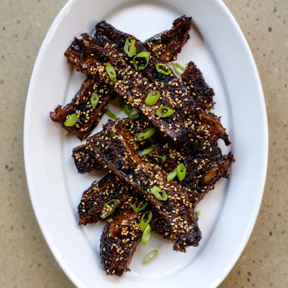 Sizzling Korean Galbi beef short ribs fresh off the grill with sesame garnish
