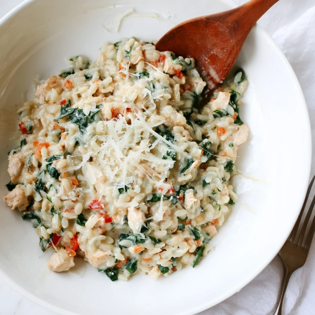 Steaming skillet of cheesy chicken risoni garnished with grated parmesan and red pepper flakes