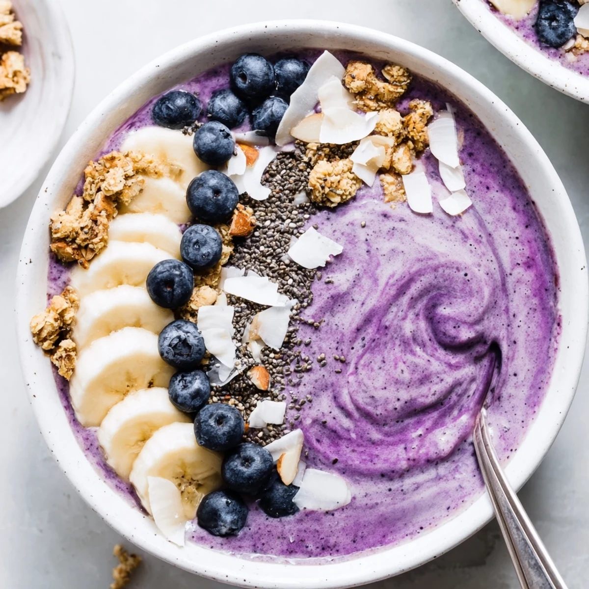 Thick creamy blueberry smoothie bowl with Greek yogurt topped with fresh berries and granola