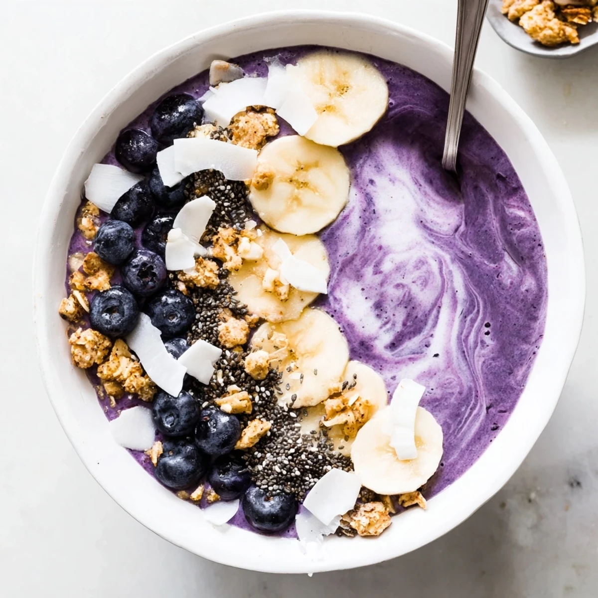 Vibrant breakfast bowl featuring blended blueberry Greek yogurt smoothie with coconut and almond toppings