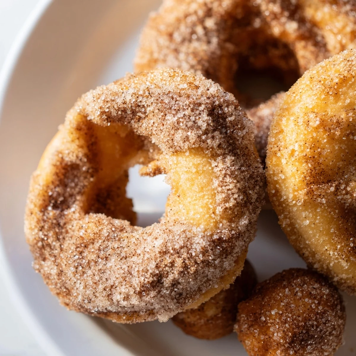 Golden pumpkin spice biscuit donuts coated in cinnamon sugar, arranged on a wooden serving board