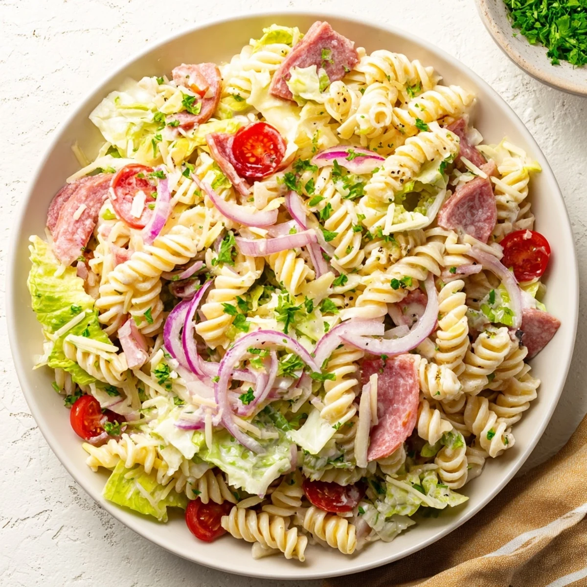 Vibrant bowl of Italian grinder pasta salad showcasing layered ingredients like pepperoni, roasted red peppers and fresh parsley garnish