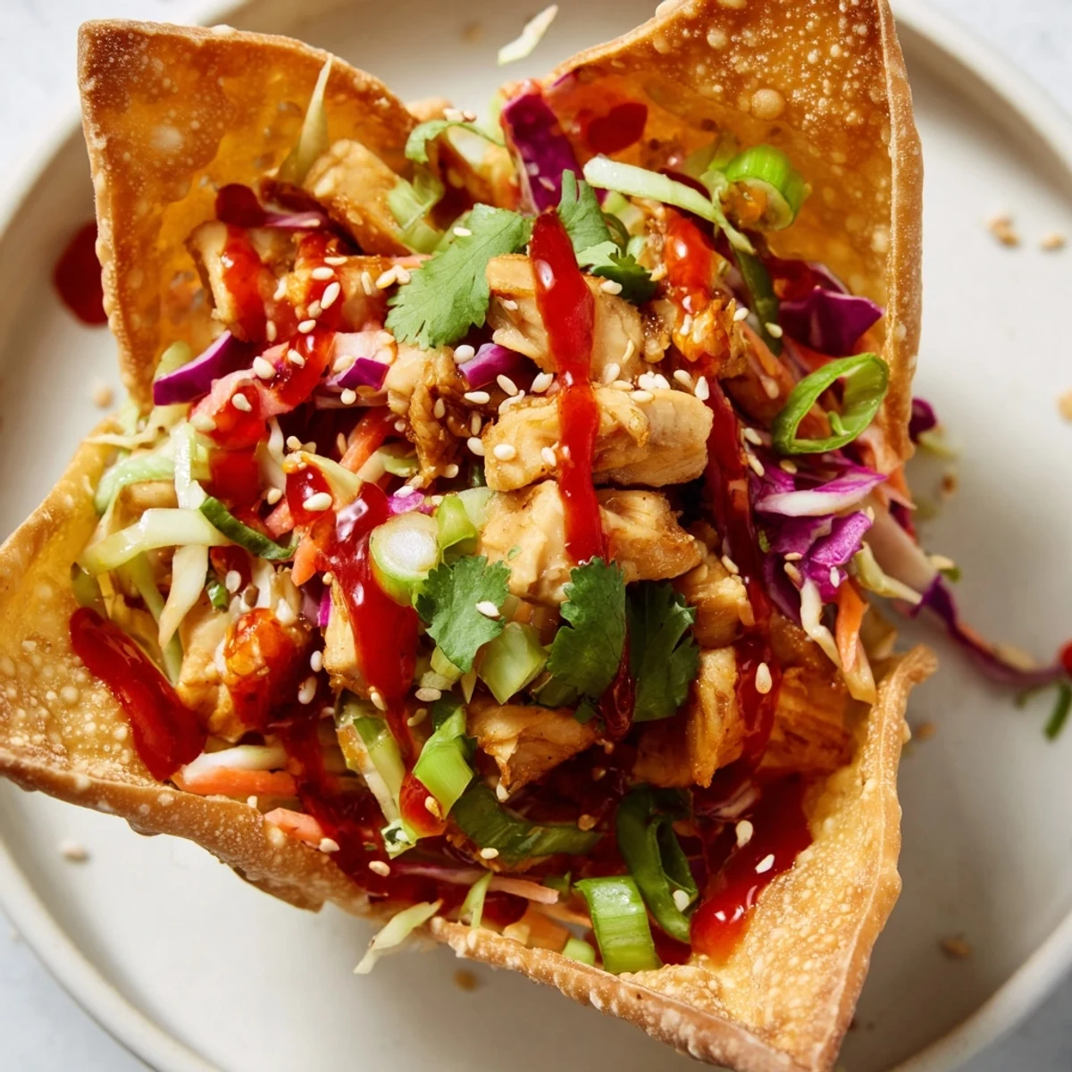 Golden crispy chicken wonton tacos topped with colorful Asian slaw and sweet chili sauce drizzle