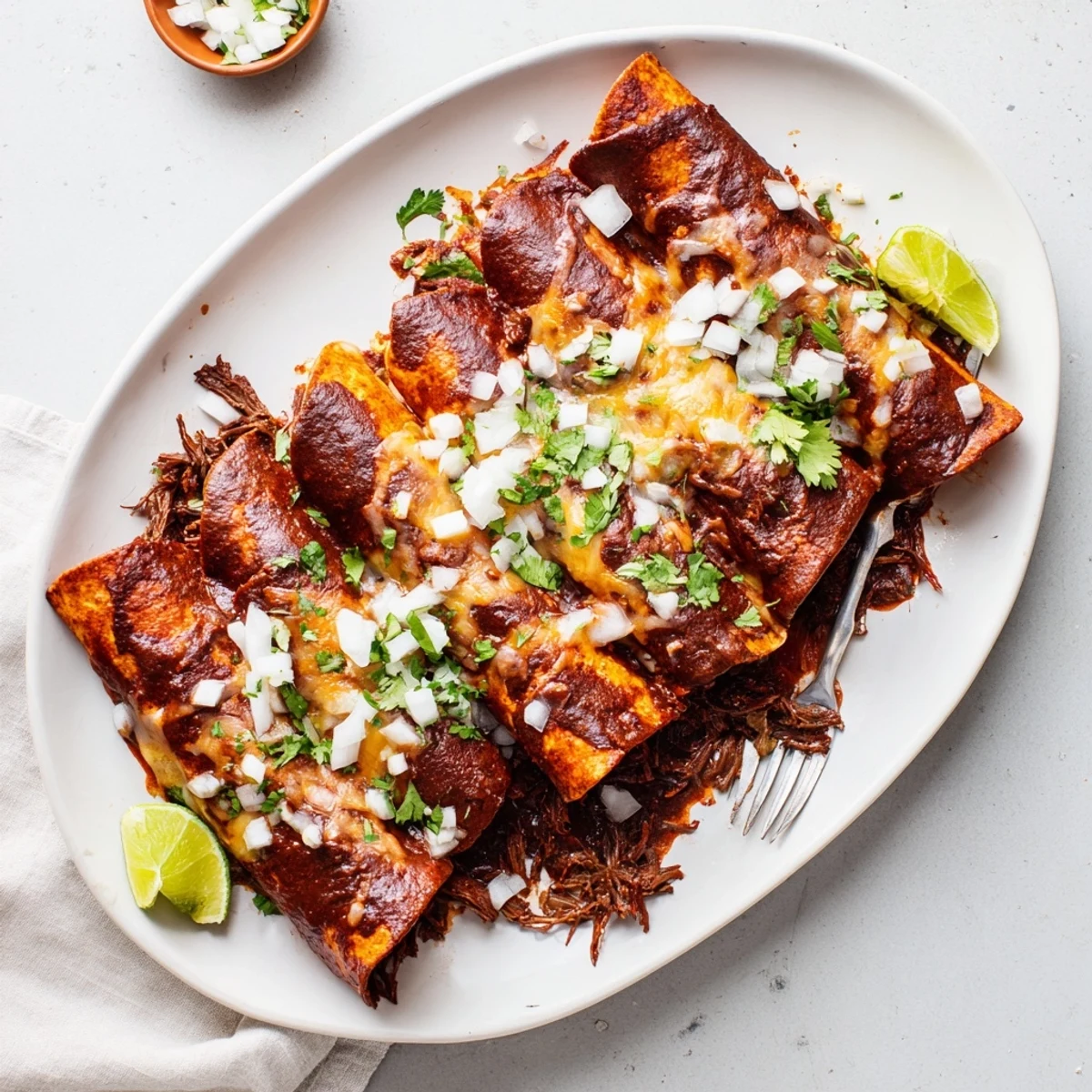 Golden birria enchiladas topped with melted cheese and fresh cilantro garnish