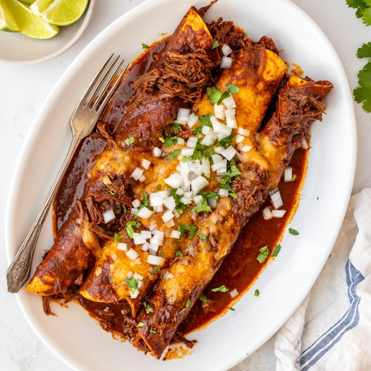Homemade birria enchiladas baking in a dish with red sauce and melted cheese topping