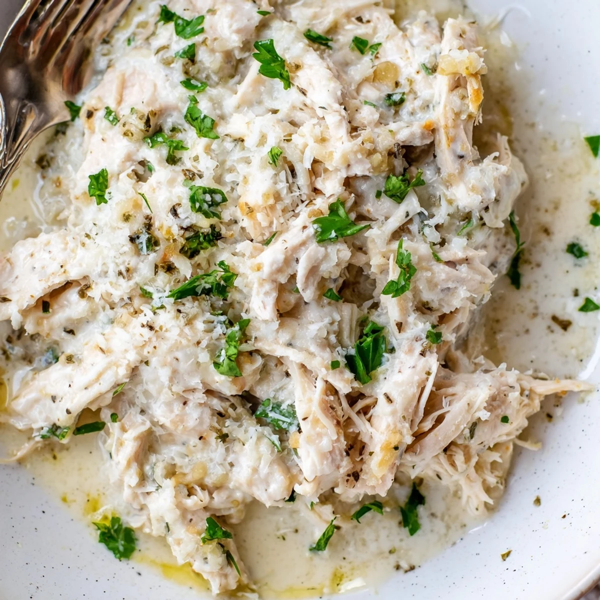 Tender slow-cooked chicken breasts swimming in a rich white garlic Parmesan sauce with herbs