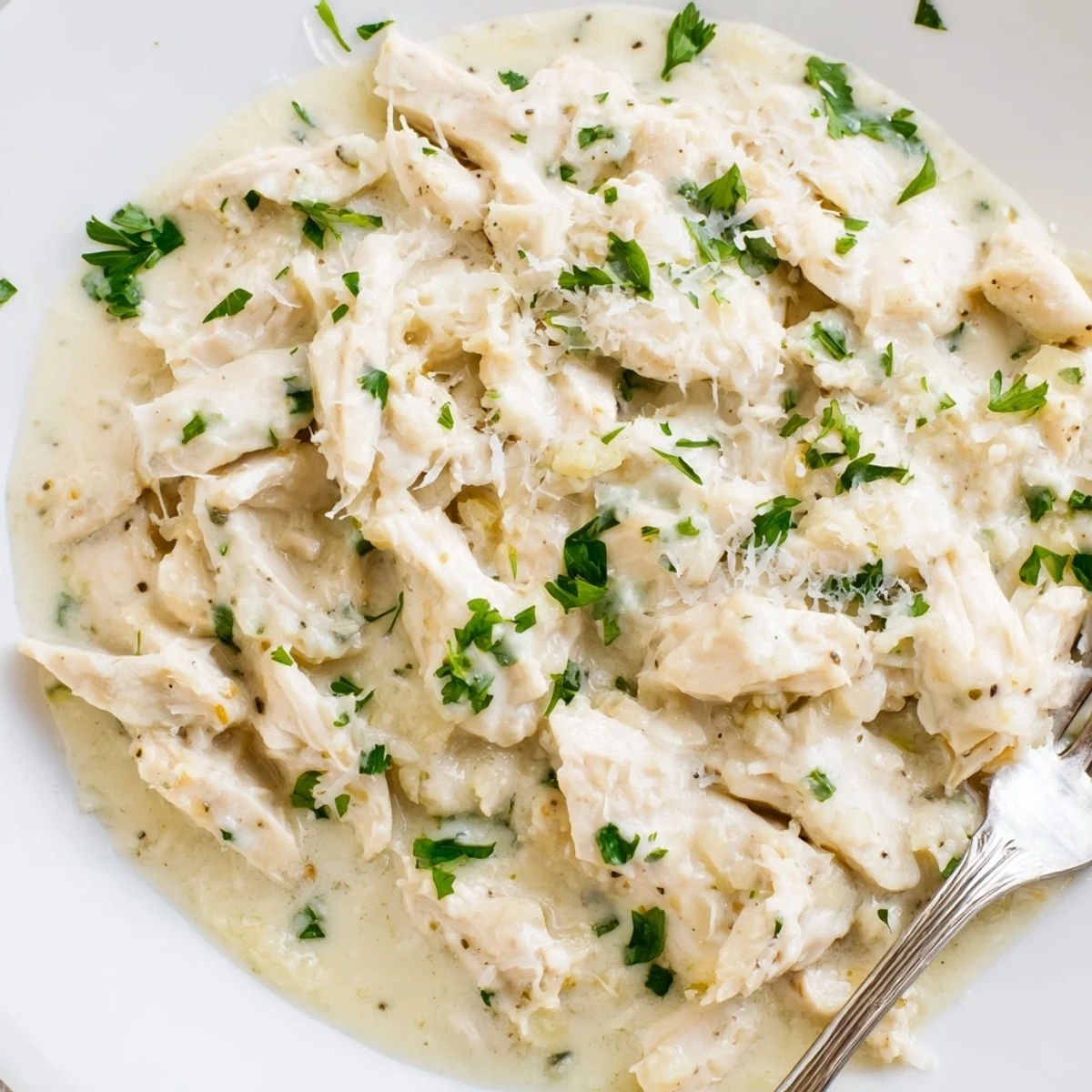 Juicy chicken slow cooker meal featuring creamy garlic Parmesan sauce and fresh parsley garnish