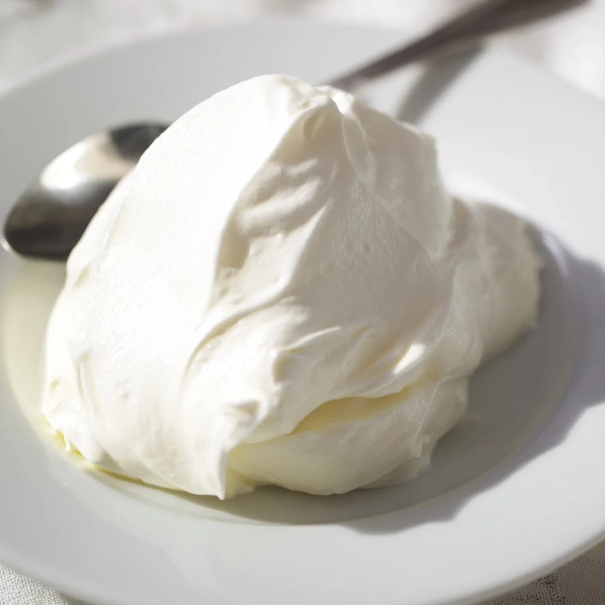 Creamy homemade Greek yogurt served in a white bowl topped with fresh honey and walnuts