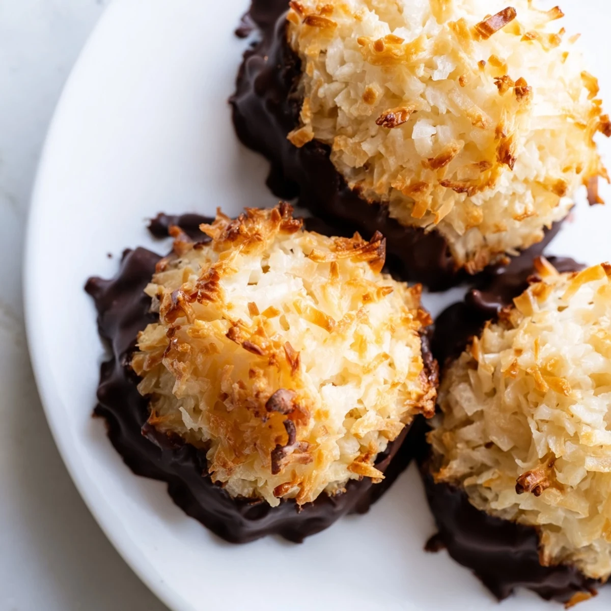 Chewy Coconut Macaroons dipped in rich chocolate, arranged on a white serving platter