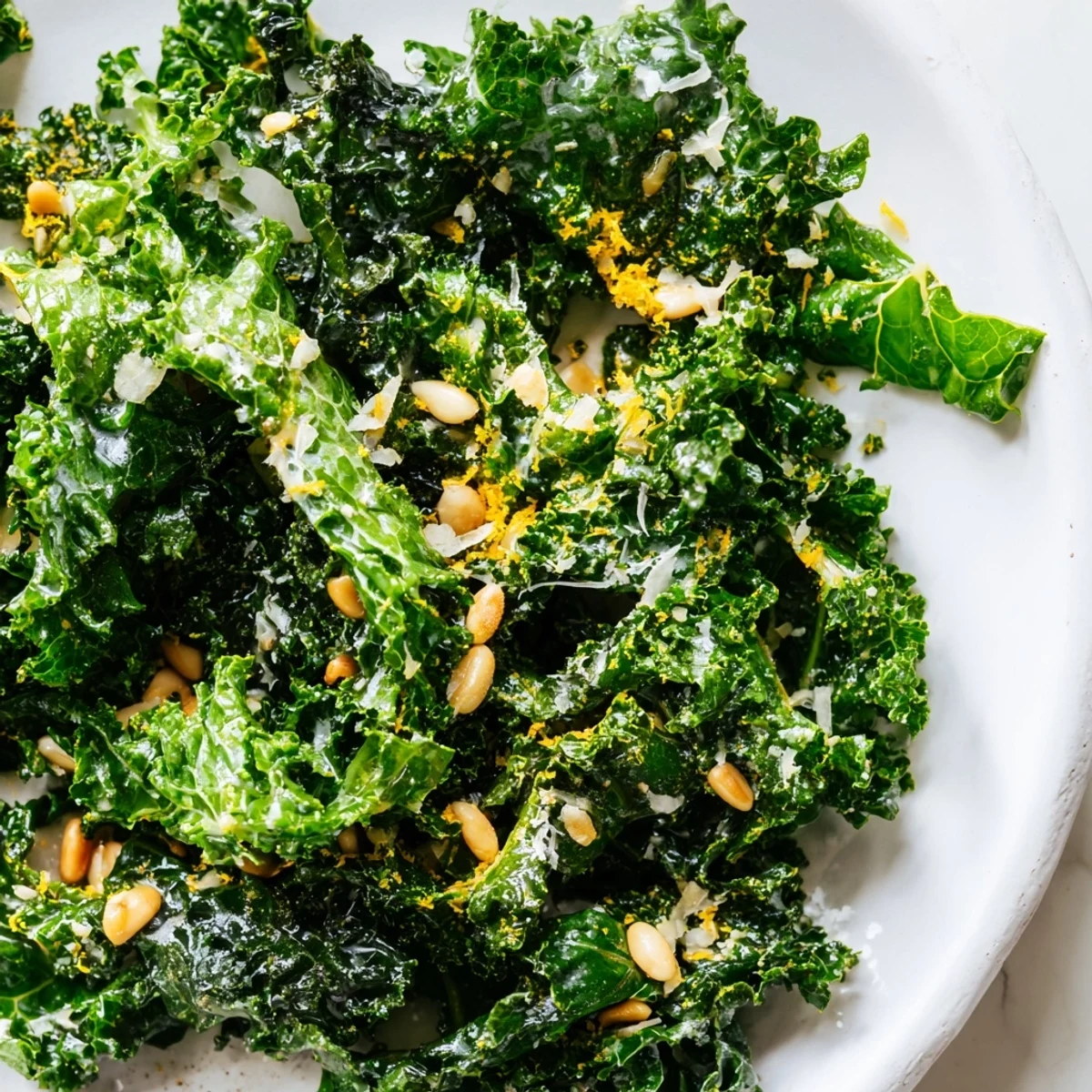 Massaged kale leaves glistening with zesty garlic lemon Parmesan dressing in wooden bowl