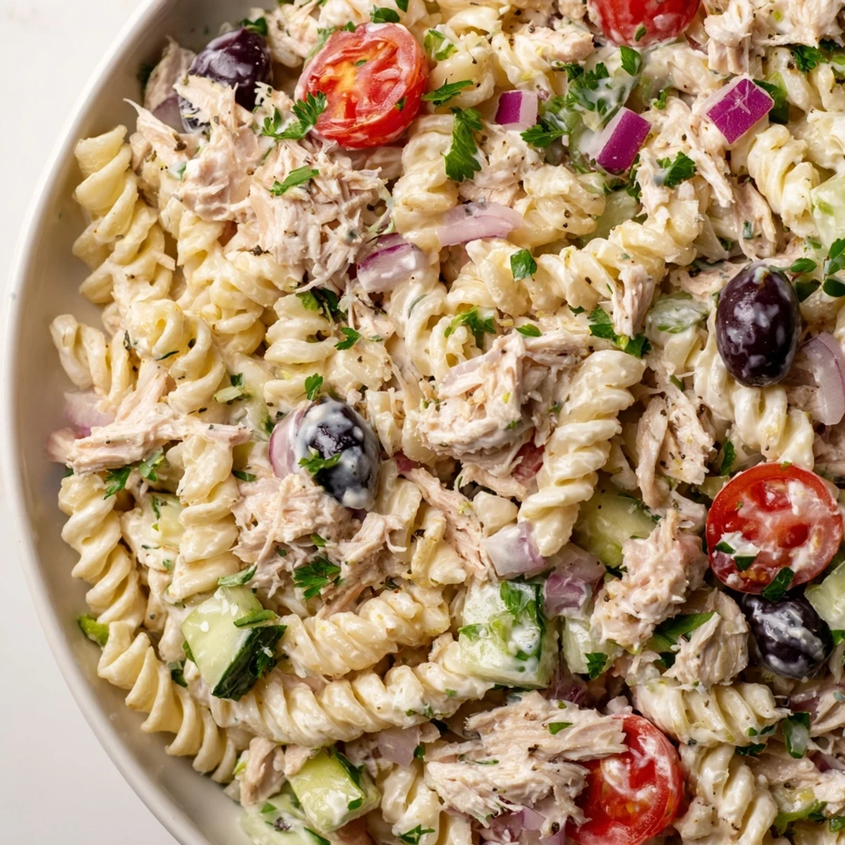 Chilled tuna pasta salad topped with ripe tomatoes, crunchy celery, and creamy dressing
